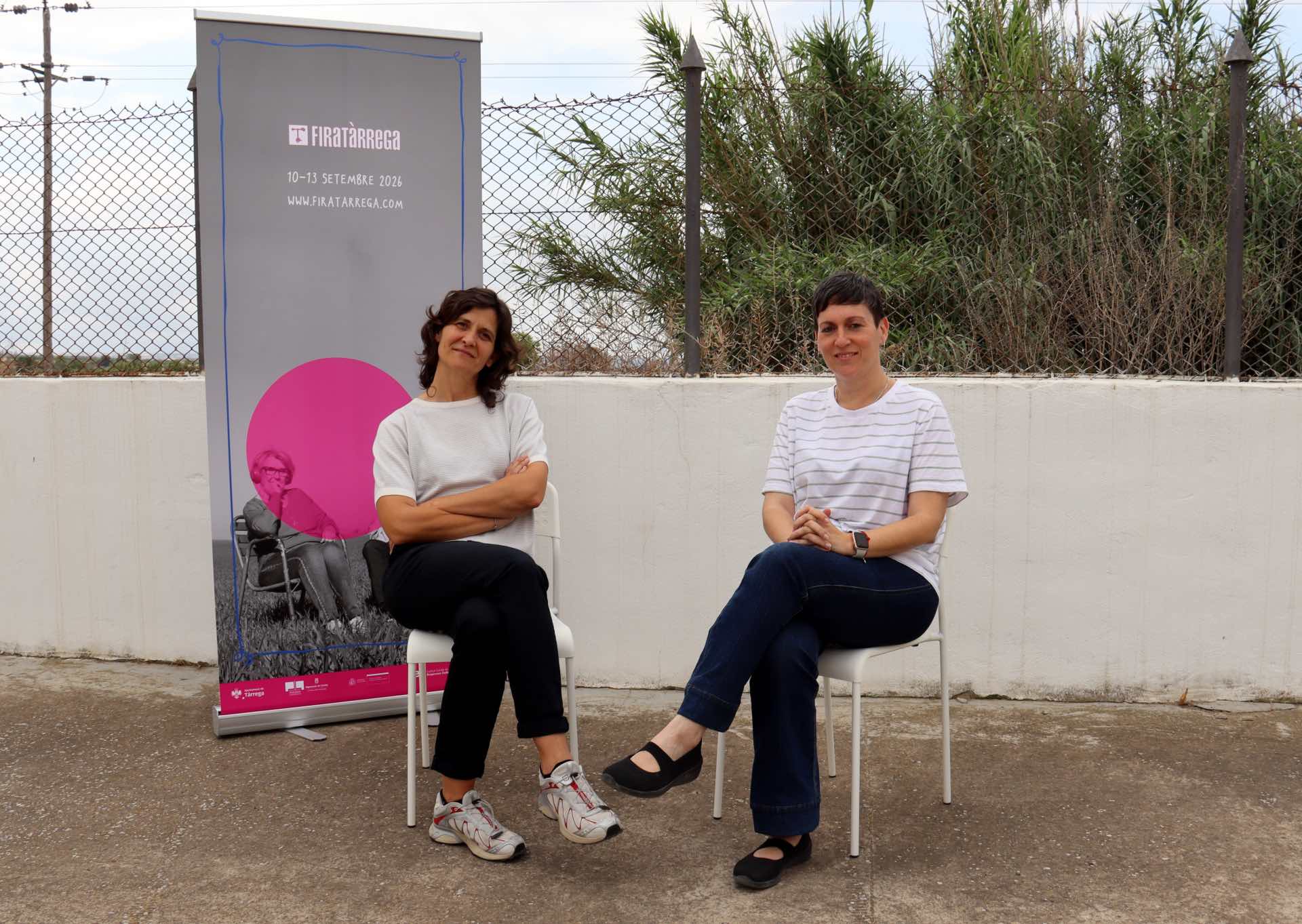 Anna Giribet, directora artística de Fira Tàrrega, i Abigail Ballester, directora executiva de Fira Tàrrega, amb el cartell de l'edició 2026