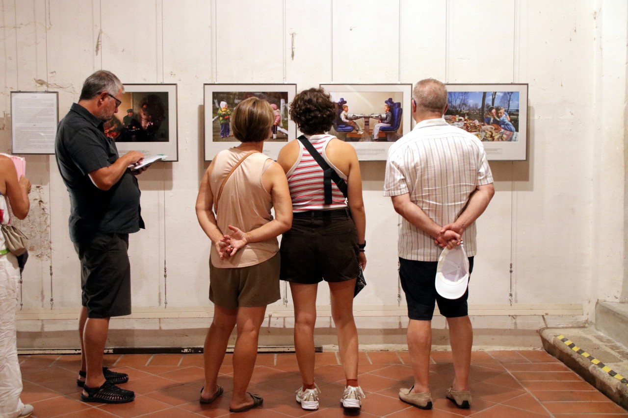 Quatre persones mirant imatges exposades al Visa pour l'Image Quatre persones mirant imatges exposades al Visa pour l'Image