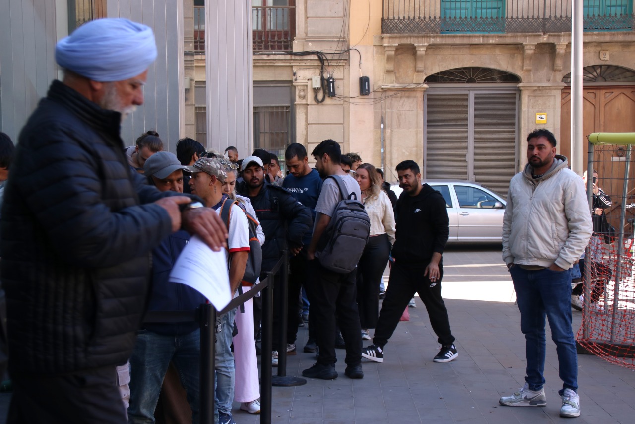 Un home mira el rellotge mentre fa cua per l'Oficina d'Atenció Ciutadana (OAC) a la plaça Sant Miquel.