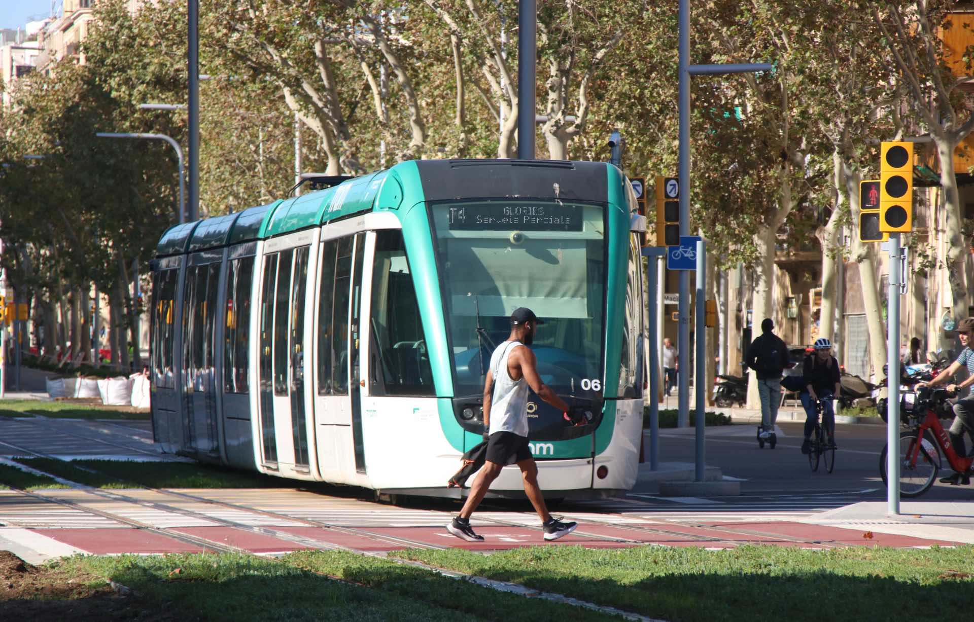 Un ciutadà creuant la Diagonal quan està a punt de passar un comboi del trambia